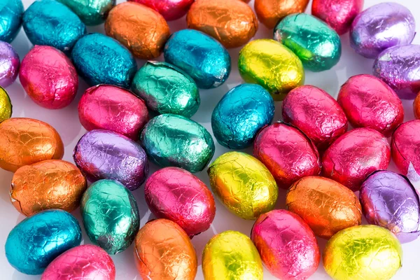 Coniglietto di Pasqua fatto di cioccolato con uovo di Pasqua su un prato verde con fiori davanti a un cielo blu — Foto Stock