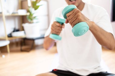 Asyalı beyaz adam evde vücut ağırlık çalıştırma egzersizi yaparken dambılı tutuyor. Spor yapıyor, sağlıklı vücut ağırlığı spor yapıyor.