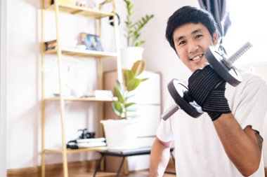 Asyalı beyaz adam evde vücut ağırlık çalıştırma egzersizi yaparken dambılı tutuyor. Spor yapıyor, sağlıklı vücut ağırlığı spor yapıyor.