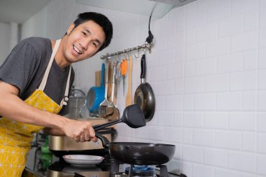 Asyalı şef tavada yumurta kızarttı, Tayland yemeği ocakta, tavada yağ kaynadı, yumurta ve domuz eti pişirildi. Mutlu bir aileye hizmet etmeden önce evde birlikte yemek yemek için.