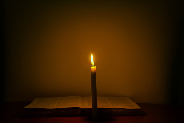Candles illuminate an open old book