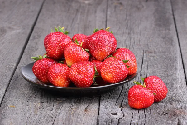 Erdbeeren auf dem Teller auf altem Holzhintergrund — Stockfoto