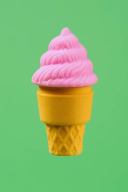 Yeşil arka planda izole edilmiş pembe sahte dondurma külahı. Lastik.