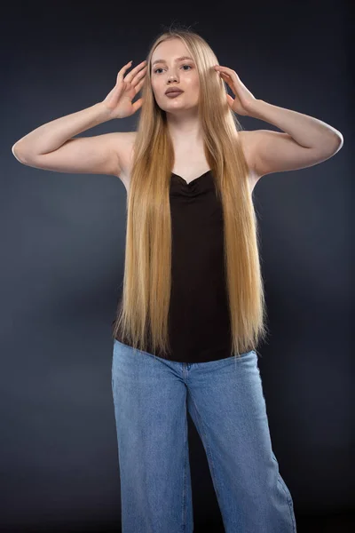 Młoda Blondynka Dżinsach Brązowy Singlet Ciemnym Szarym Tle — Zdjęcie stockowe