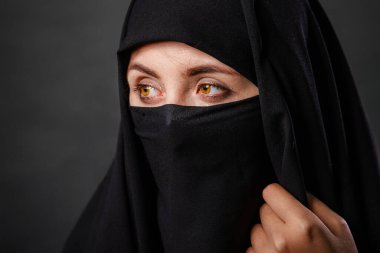 Siyah burka giyen, siyah arka planda izole edilmiş genç ve yetişkin bir kadının portresi..