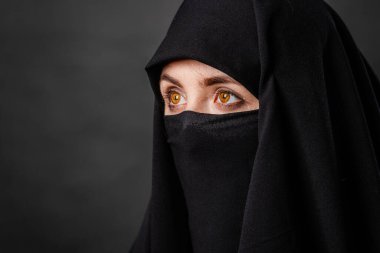 Siyah burka giyen, siyah arka planda izole edilmiş genç ve yetişkin bir kadının portresi..