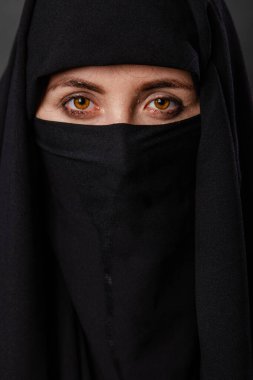 Siyah burka giyen, siyah arka planda izole edilmiş genç ve yetişkin bir kadının portresi..