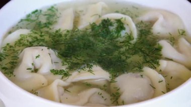 Çorba kabında sebzeli hamur köftesinin seçici odak noktası. Yemekten sıcak buhar yükselir..