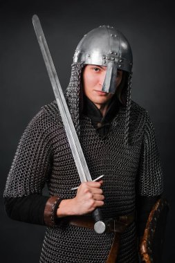 Viking döneminin ortaçağ savaşçısının portresi ve Haçlı Seferleri 'nin başlangıcı. Zincirli zırhlı ve kasklı bir şövalye. Kalkanları ve kılıçları var. Karanlık bir arka planda..