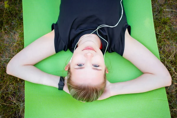 Aantrekkelijk Meisje Met Hoofdtelefoon Luistert Naar Muziek Terwijl Een Groene — Stockfoto