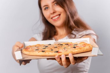 Seçici odak, beyaz bir arka planda izole edilmiş, kadınların elindeki bir kutuda parçalanmış bir pizzayı kapat..