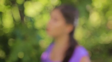 Bokeh 'ten ortaçağ elbisesi giymiş çekici bir kadının portresine doğru pürüzsüz bir odaklanma hareketi. Bir parkın arka planında, ormanda. Seçici odak.