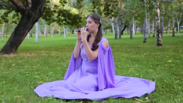 Young Attractive Woman Make Medieval Dress Plays Ocarina Sitting Grass — Stock Video