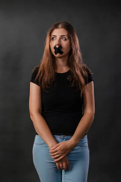 黒いテープで口を塞いだ若い女性の肖像 言論の自由の制限 暗い背景に隔離された発言と意見表明の禁止 — ストック写真