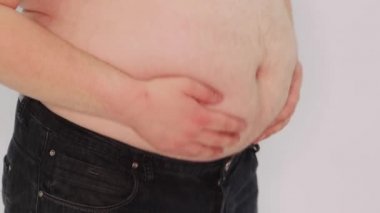 Koca göbeğini sallayan şişman bir adamın yakın plan beyaz bir arka planda izole edilmiş ellerinin görüntüsü..