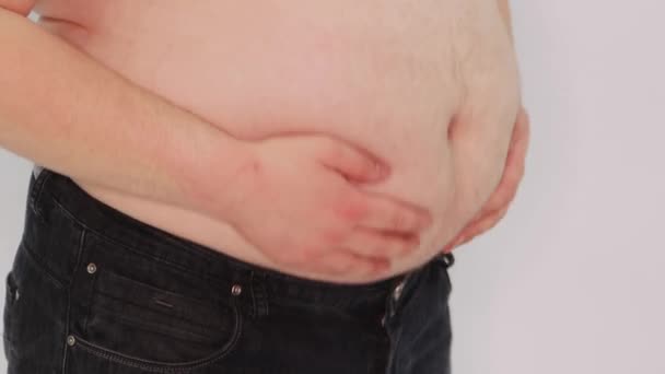 一个肥胖男人的特写镜头 他用双手在白色背景下抖动着他的大肚子 — 图库视频影像