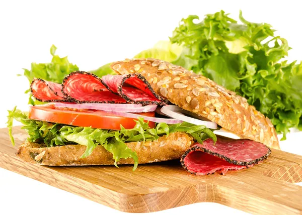 白いまな板の上の完全なトウモロコシのパンとサラミのサンドイッチ — ストック写真