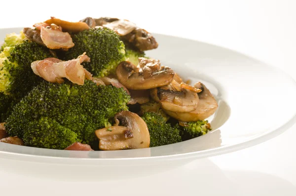 Brócoli salteado con tocino, cebolla y champiñones en plato blanco — Foto de Stock
