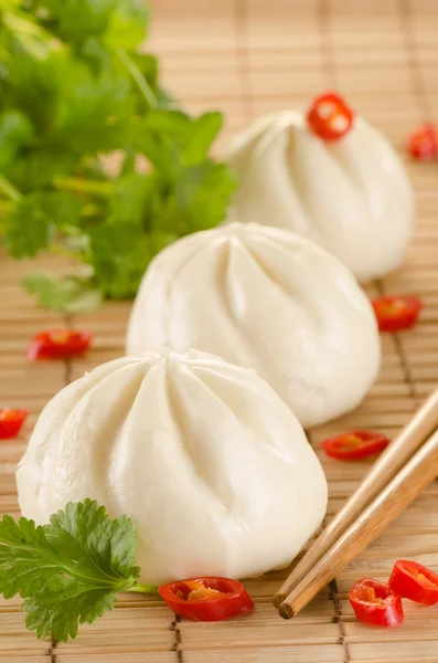 Chinesisch gedämpfte Brötchen auf der Bambusmatte Hintergrund mit Koriander, — Stockfoto