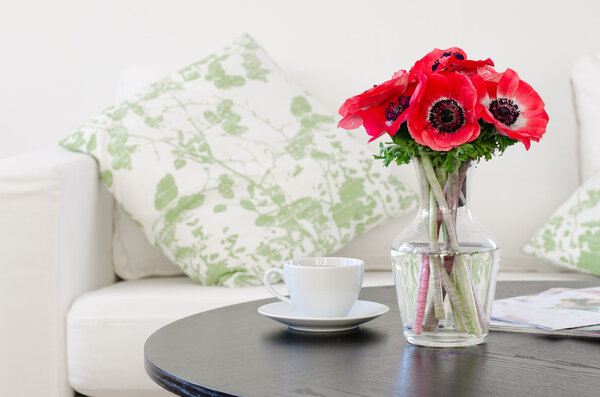 Vase of red flowers in modern white living room