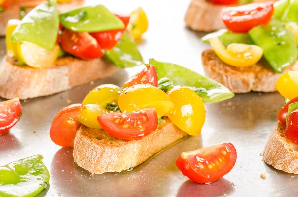 Cherry tomatoes and snow peas crostini — Stock Photo, Image
