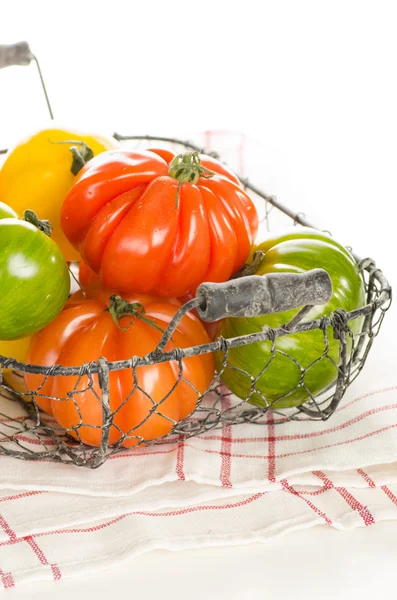 Fresh heirloom tomatoes in a basket isolated on white — Stock Photo, Image