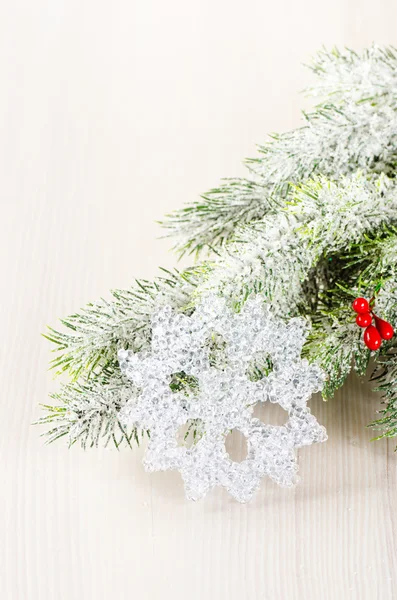 Weihnachtsbaumzweige mit Schneeflocke auf hellem Holzhintergrund — Stockfoto