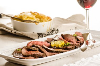 Slices of roast beef with potato gratin clipart