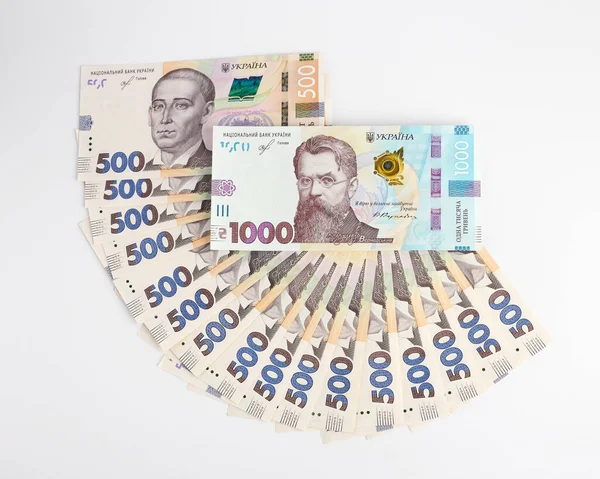 500 Hryvnia banknotunun üstünde 1000 Hryvnia banknotu var. Banknotlar beyaz arka planda yatar. Yukarıdan görüntüle