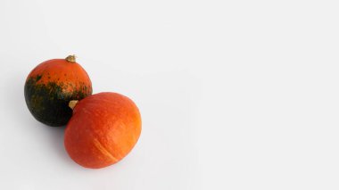 Beyaz arka planda Hokkaido balkabakları. Balkabakları sol alt köşede yer alıyor. Ön- üstü görünümü