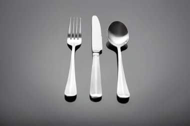 Çatal takımı - çatal, masa bıçağı ve masa kaşığı gri parlak arka planda.