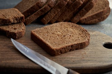 Tahtada bir parça çavdar ekmeği. Arka planda dilimlenmiş çavdar ekmeği