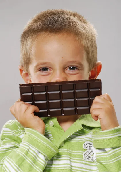 Kleine jongen jongetje eten chocolade chocolade bar, houden, — Stockfoto