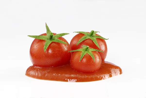 Trzy małe pomidory i krem na białym tle. — Zdjęcie stockowe