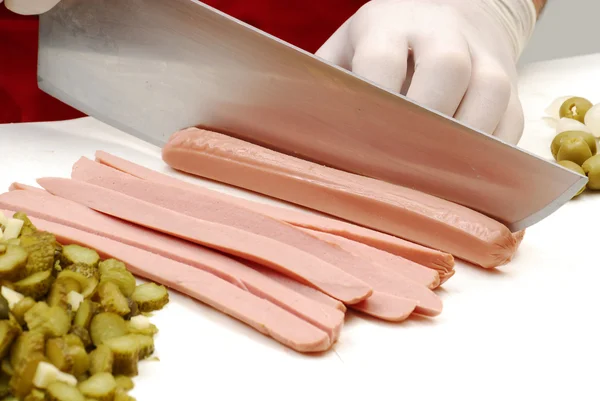 Cutting cucumber and sausage in a white table. — Stock Photo, Image