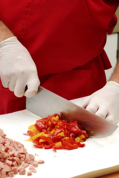 Corte, pimientos rojos, pimentón y salchichas en una cocina . — Foto de Stock