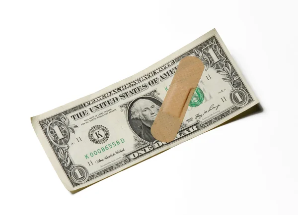 Conta de dólar com ajuda de banda adesiva no fundo branco . Fotografias De Stock Royalty-Free