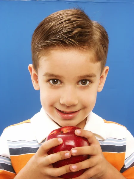 Glad liten pojke som håller ett rött äpple — Stockfoto