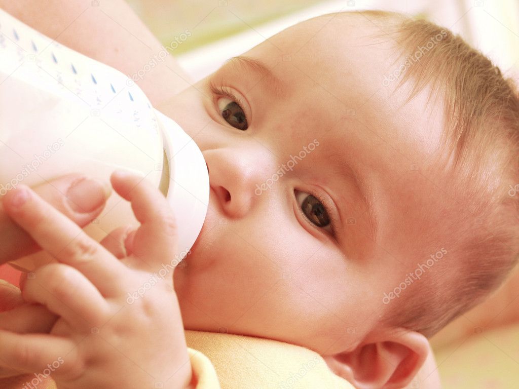 Mother is feeding her baby boy with a baby bottle