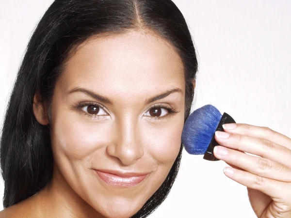 Latin woman applying blush on white background. — Stock Photo, Image