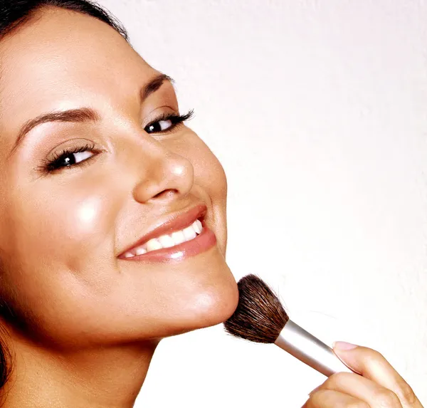 Latin woman applying blush on white background. — Stock Photo, Image