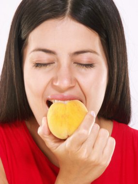 Young woman eating a peach on white background clipart