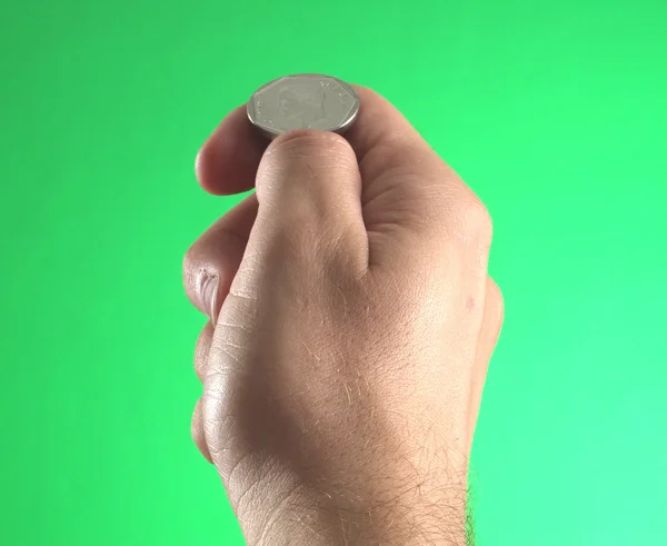 Ręka trzyma monetę na zielonym tle — Zdjęcie stockowe