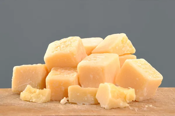 Parmezán sajtot kockákra egy fa asztal. — Stock Fotó