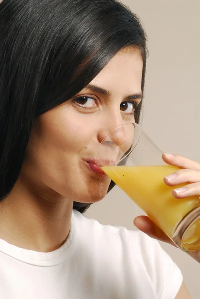 Mladá žena pije pomerančový džus — Stock fotografie