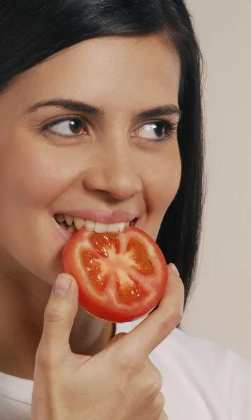 Jovem latina comendo tomate — Fotografia de Stock