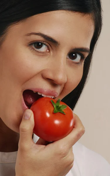 Jovem latina comendo tomate — Fotografia de Stock