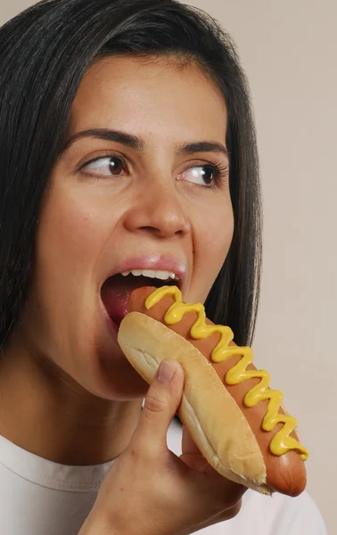 Mujer joven comiendo perrito caliente — Foto de Stock