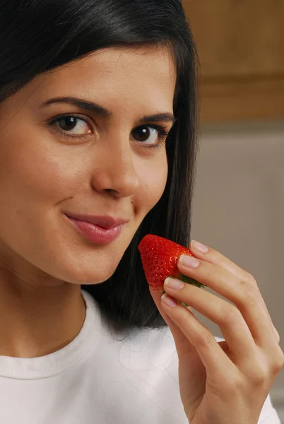 Young woman holding a fresh strawberry on white background — Stock Photo, Image