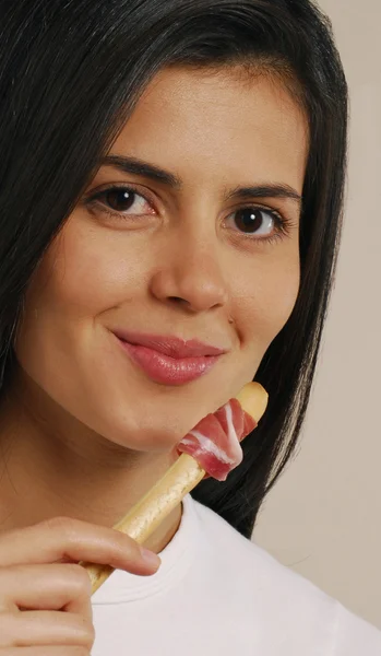 Mujer joven comiendo prosciutto crudo y grissini —  Fotos de Stock